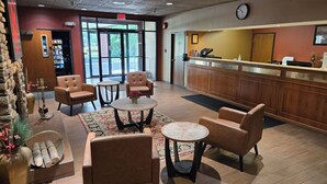A lobby with leather chairs, a reception desk, and a clock on the wall. - Fulton Hotel - Oswego Riverfront (Fulton)