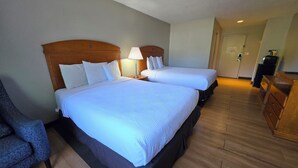 A hotel room with two beds, a desk, a chair, and a wardrobe. - Fulton Hotel - Oswego Riverfront (Fulton)