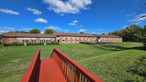 A large brick building with a flat roof, likely a school or community center, with a red pathway leading to the entrance. - Fulton Hotel - Oswego Riverfront (Fulton)