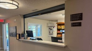 A hotel reception area with a reception desk, a computer, a telephone, and a wall-mounted sign.