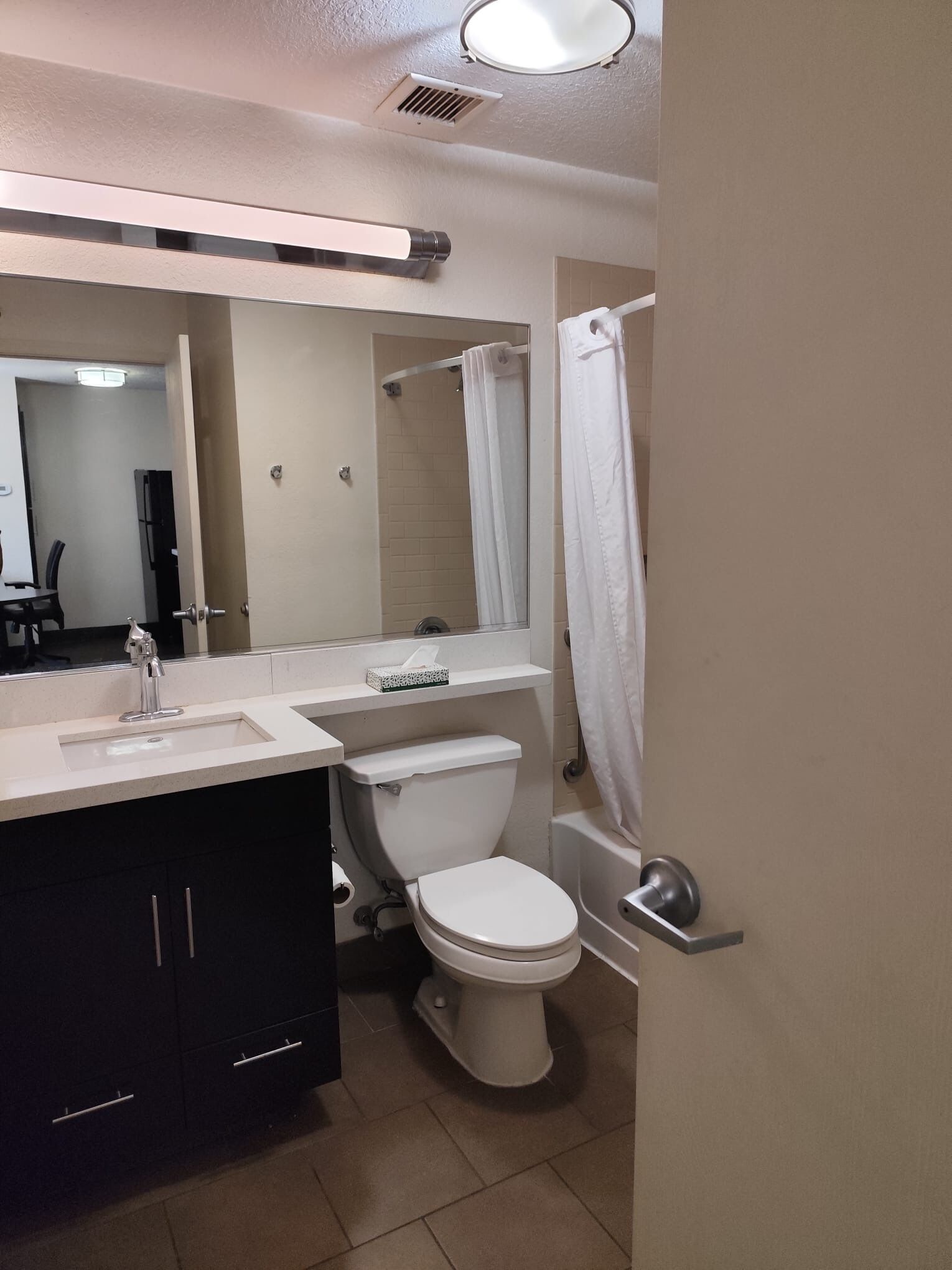 A bathroom with a toilet, sink, mirror, and shower curtain.