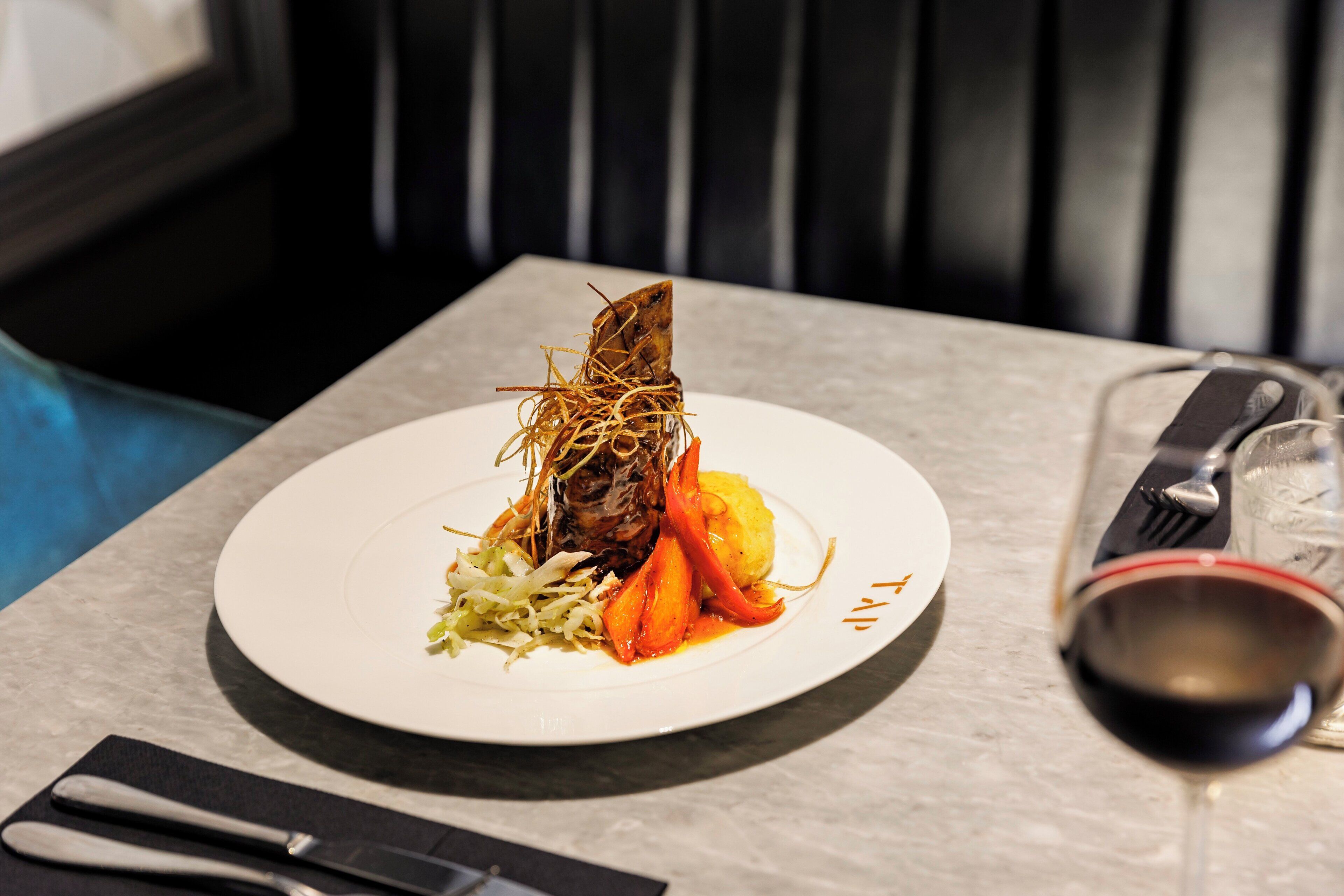 A dining table with a plate of food, a wine glass, and cutlery.