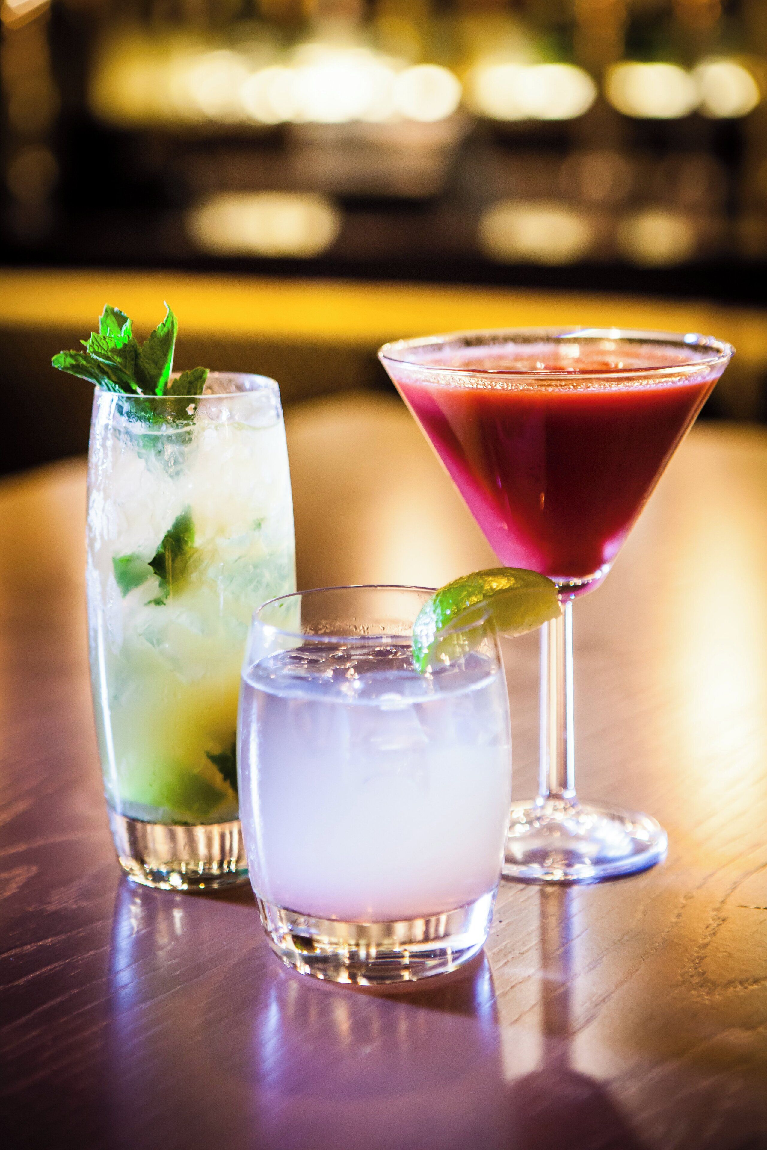 Tres tipos de bebidas en vasos sobre una barra.