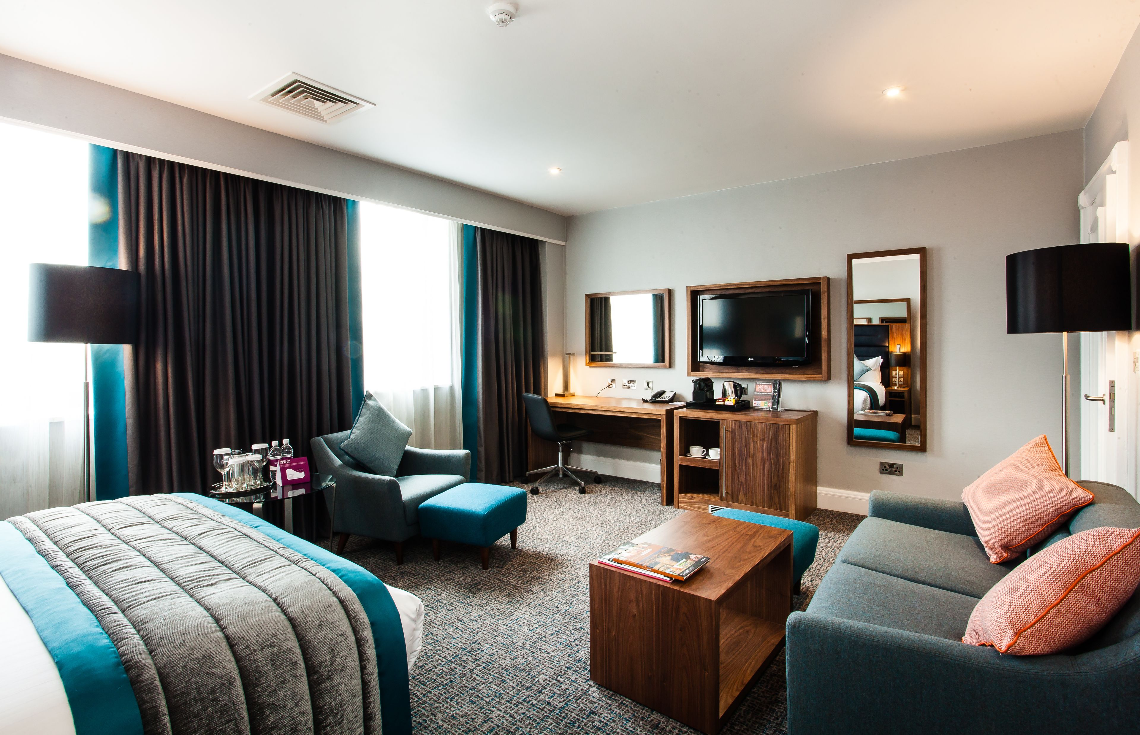 Une chambre d’hôtel équipée d’un lit, d’un bureau, d’un ordinateur, d’une télévision et d’un canapé.