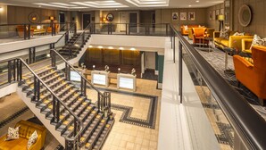 A hotel lobby with a central staircase, multiple seating areas, and a reception desk. - Crowne Plaza Leeds by IHG (Leeds)