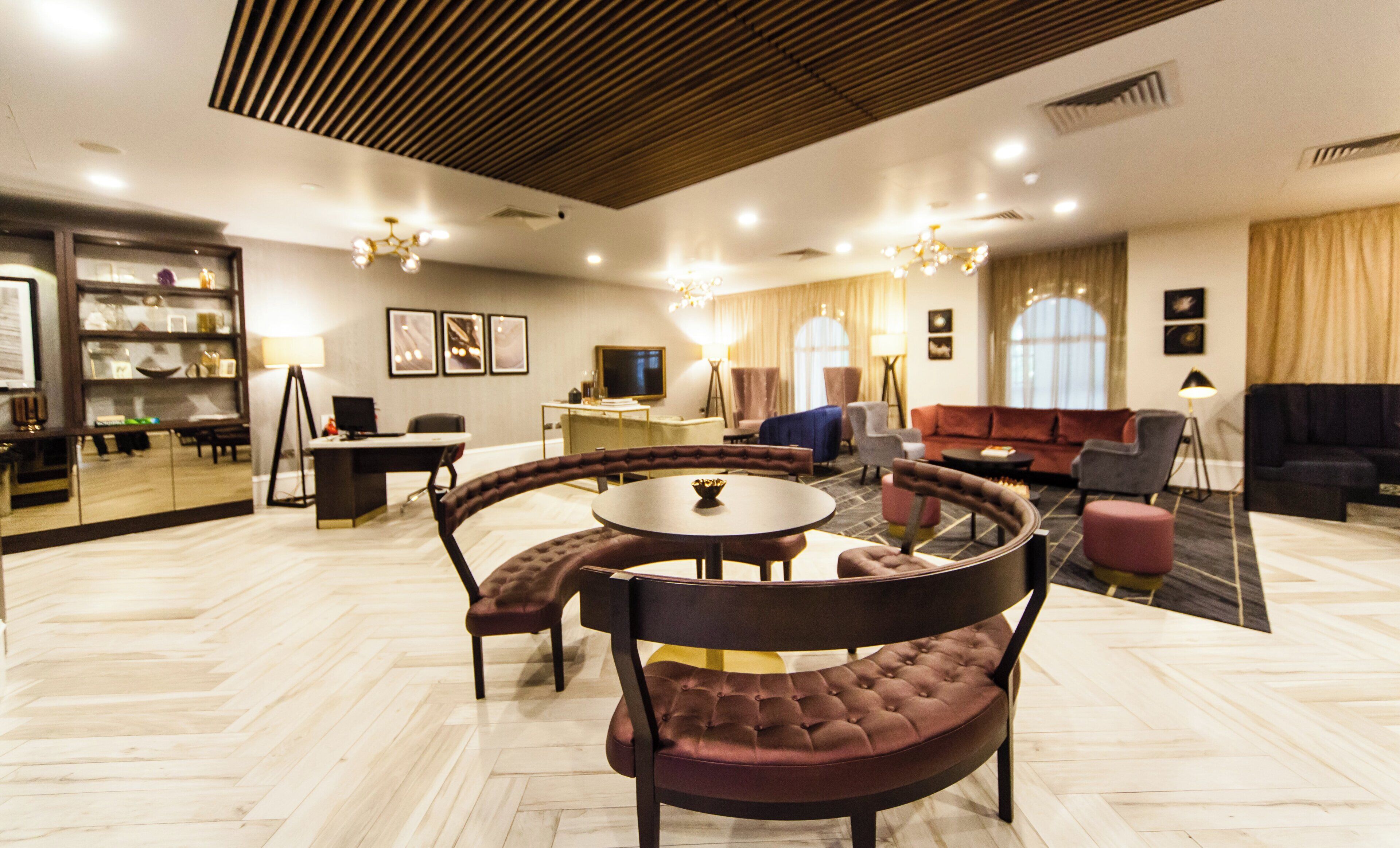 Un moderno vestíbulo de hotel con una mesa redonda, zona de estar y un televisor.