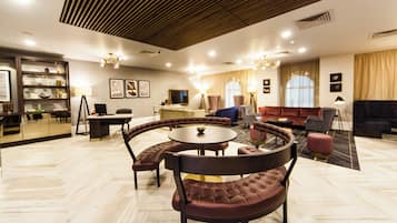 Un moderno vestíbulo de hotel con una mesa redonda, zona de estar y un televisor.