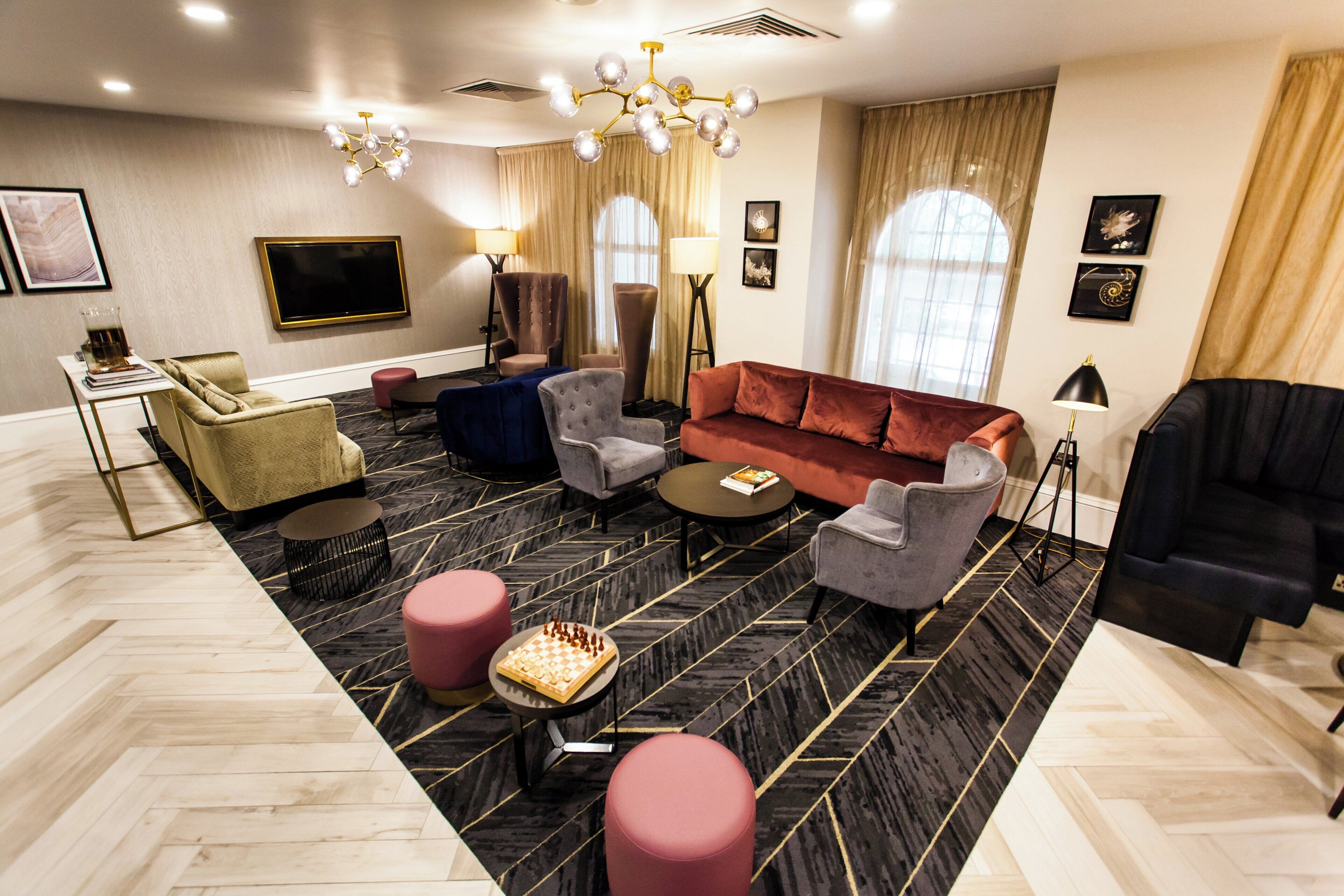 Una sala de estar moderna con sofá, sillones, mesa de centro, televisor y una araña.
