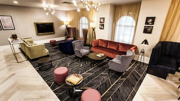 A modern living room with a sofa, armchairs, a coffee table, a TV, and a chandelier.