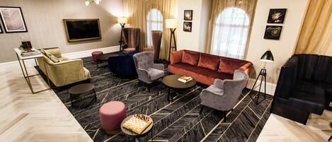 Una sala de estar moderna con sofá, sillones, mesa de centro, televisor y una araña.