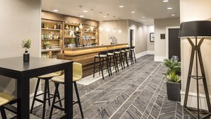 A bar area with a counter, stools, and shelves stocked with bottles. - Crowne Plaza Leeds by IHG (Leeds)