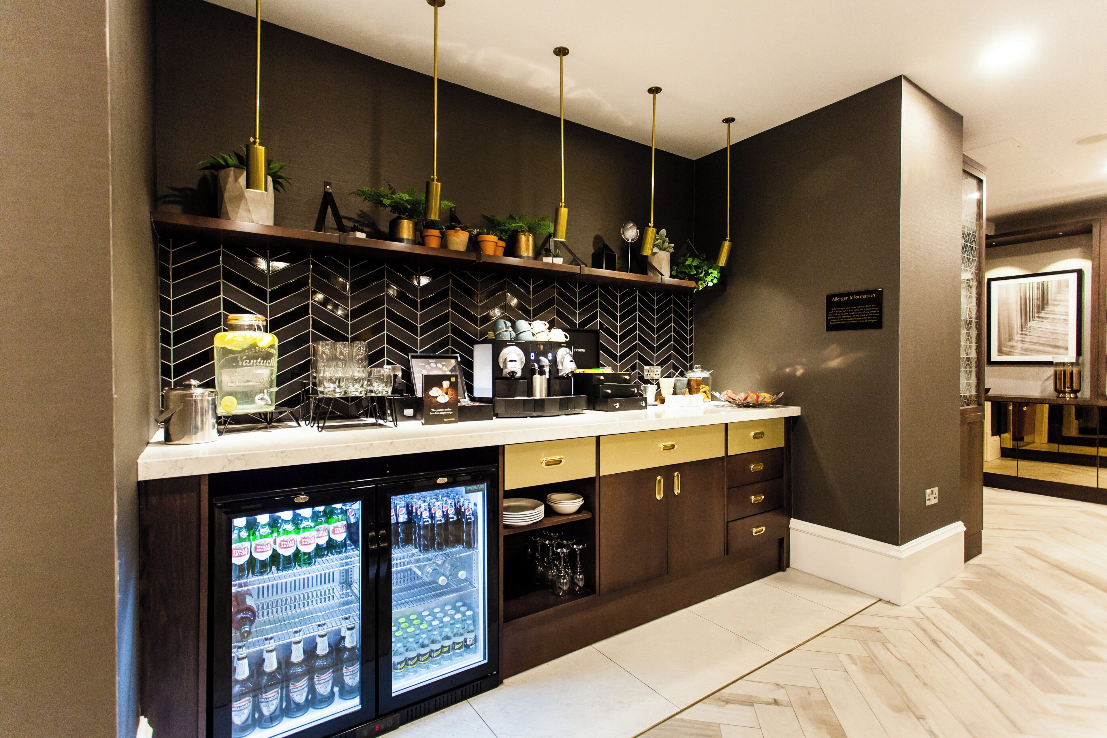 A modern kitchen with a herringbone tile backsplash, a built-in refrigerator, and a coffee station.