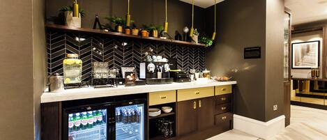 A modern kitchen with a herringbone tile backsplash, a built-in refrigerator, and a coffee station.