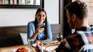 Una mesa de comedor con platos de comida y copas de vino.