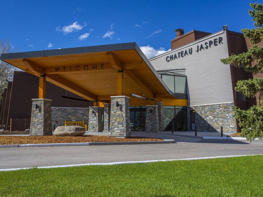 A hotel entrance with a 'Welcome' sign, stone pillars, and a modern architectural design.