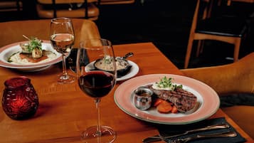 A dining table with plates of food, wine glasses, and cutlery.
