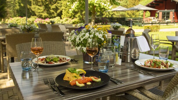 Un espacio de comedor al aire libre con mesas, sillas y sombrillas.