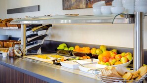Una mesa de buffet con frutas, pasteles y salsas.