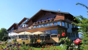 A two-story building with balconies, large windows, and outdoor seating with umbrellas. - Airporthotel Salzburg (Salzburg)