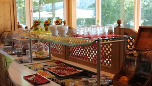 A buffet setup with various food items and a glass display case. - Airporthotel Salzburg (Salzburg)