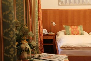 Ein Hotelzimmer mit einem Holzkopfteil, einem Nachttisch mit Lampe, Telefon und einem Zierkissen.