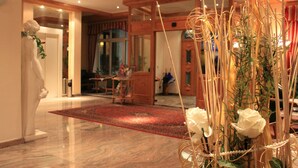 A hotel lobby with a marble floor, wooden beams, a red carpet, and a white statue. - Airporthotel Salzburg (Salzburg)