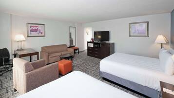 A hotel room with a bed, a sofa, a desk, a television, and a microwave.