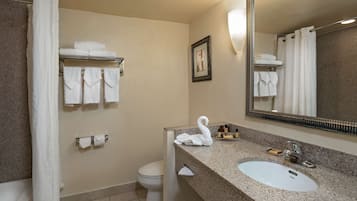 Un baño con lavamanos, espejo, toallero y retrete.