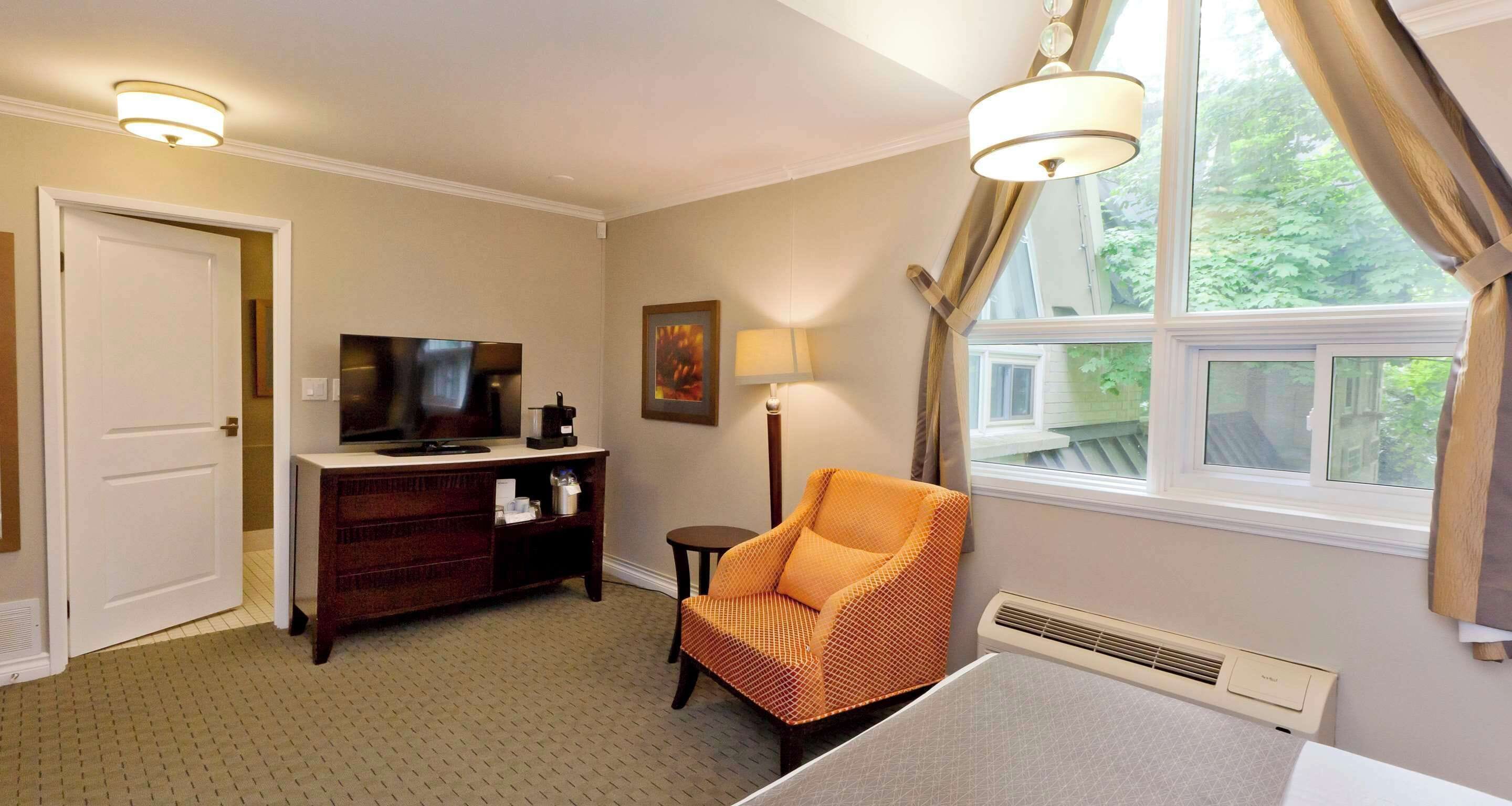 Una habitación de hotel con cama, televisor, escritorio con lámpara y una silla.