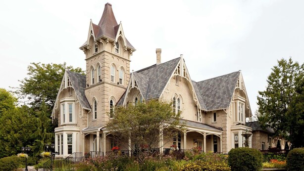 A large, historic house with a prominent tower, multiple chimneys, and a well-maintained garden. - Elm Hurst Inn & Spa, WorldHotels Crafted (Ingersoll)