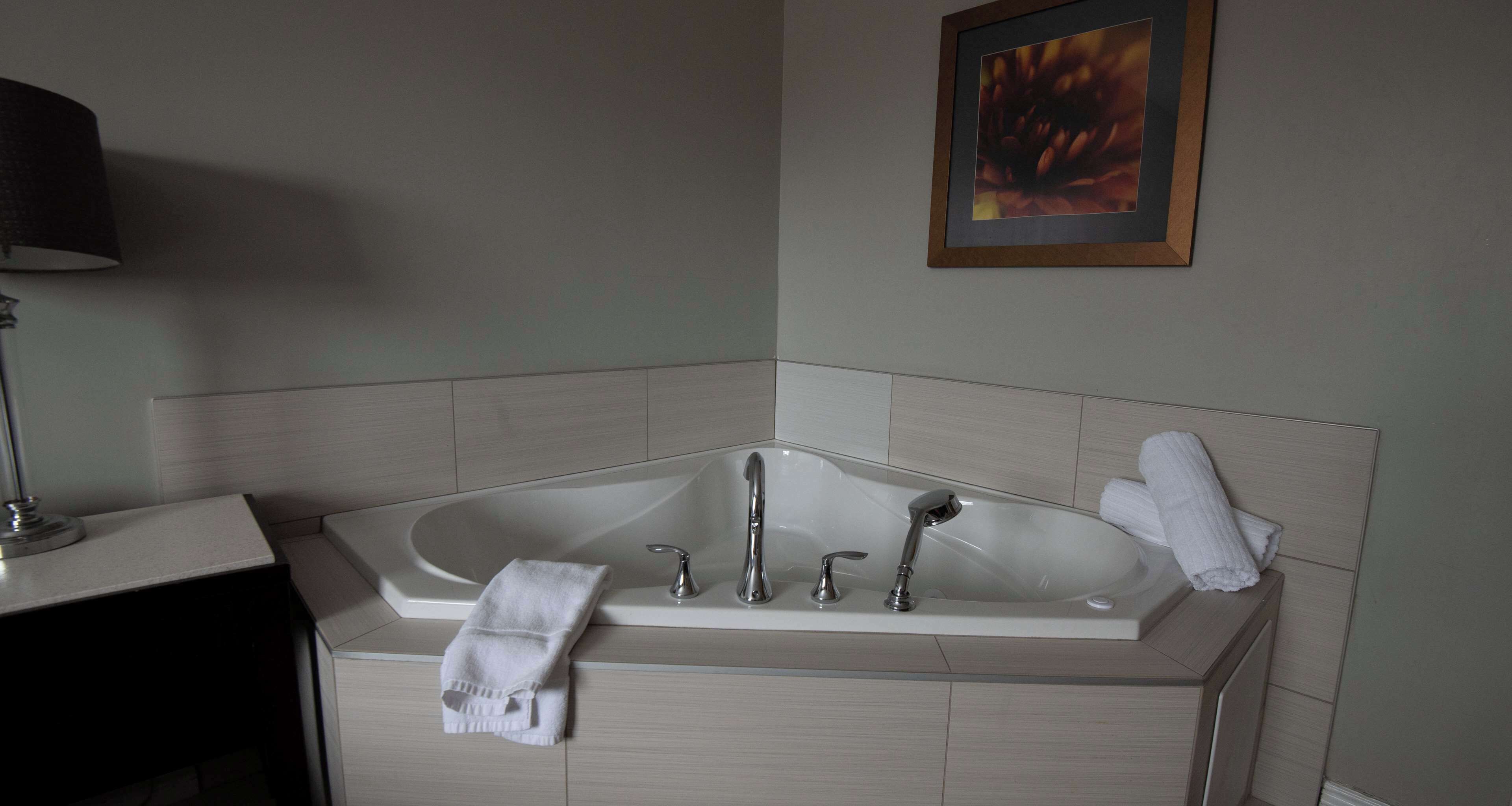 Un baño moderno con una bañera independiente, un tocador con un espejo y una lámpara, y un cuadro en la pared.