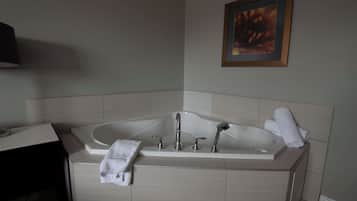 Un baño moderno con una bañera independiente, un tocador con un espejo y una lámpara, y un cuadro en la pared.