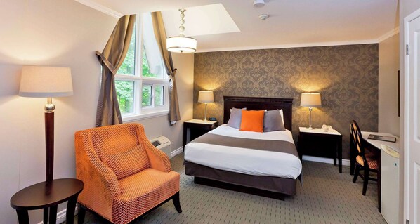 A hotel room with a bed, two bedside tables, a chair, a desk, and a window with curtains.