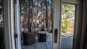 A glass door leading to an outdoor seating area with wicker furniture and a fire pit. - Elm Hurst Inn & Spa, WorldHotels Crafted (Ingersoll)
