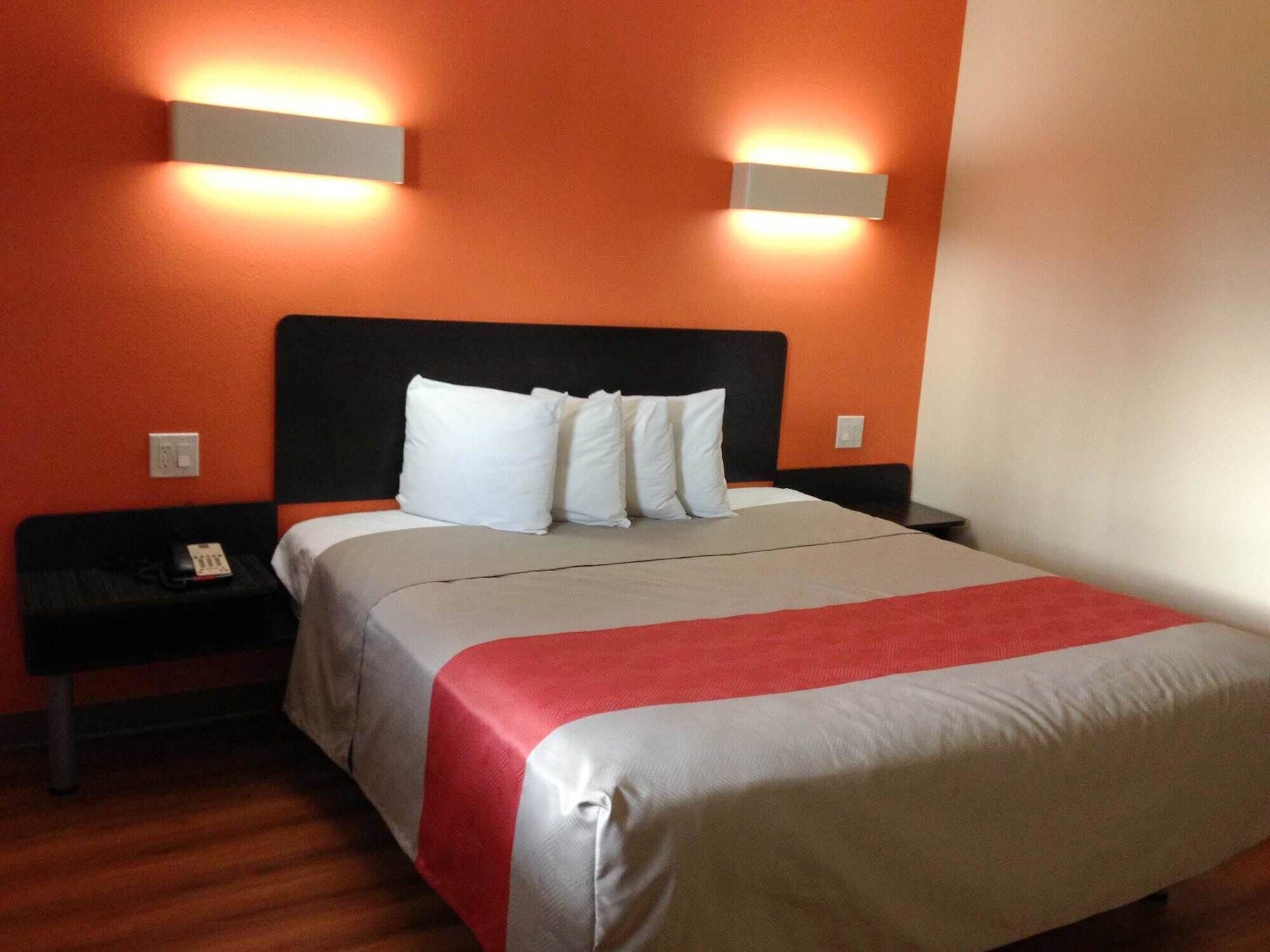 A hotel room with a large bed, two bedside tables, and two wall-mounted lights.