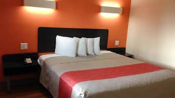 A hotel room with a large bed, two bedside tables, and two wall-mounted lights.
