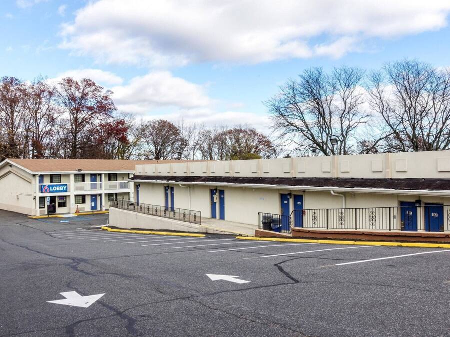 A motel with a two-story building, a parking lot, and a clear sky.
