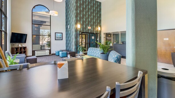 A modern conference room with a large table, comfortable seating, and a large window offering a view of the outdoors. - Quality Inn near MCAS Cherry Point (Havelock)