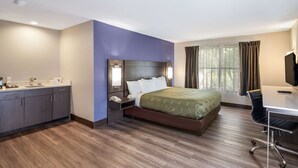 A hotel room with a bed, a desk, a chair, a nightstand, and a window with curtains. - Quality Inn near MCAS Cherry Point (Havelock)