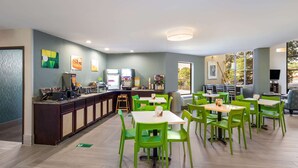 A restaurant with green chairs and tables, a counter with a coffee machine, and artwork on the walls. - Quality Inn near MCAS Cherry Point (Havelock)