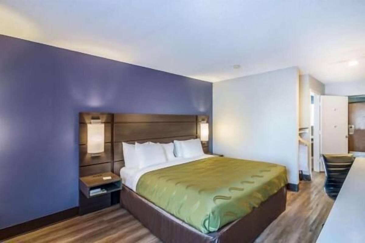 Une chambre d’hôtel avec un lit, des tables de chevet et une porte.