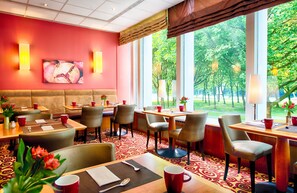Enjoy meals in a stylish dining area with a view of lush gardens, comfortable booths and tables, and elegant table settings.
