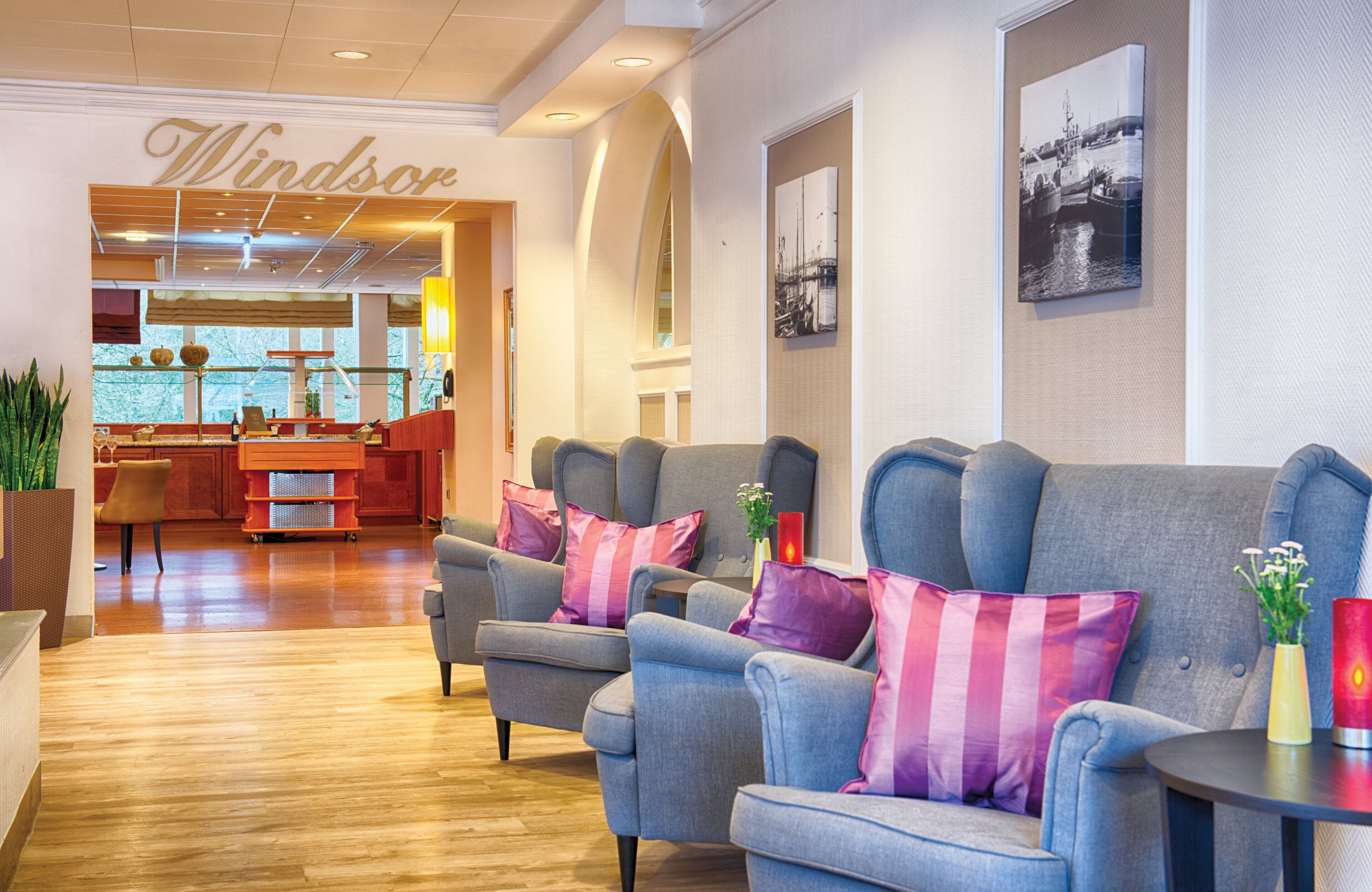 A hotel lobby with a reception desk, seating area, and a view of the outdoors.