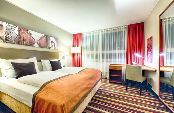 Relax in comfort with a large bed, desk, and mirror in this inviting room.