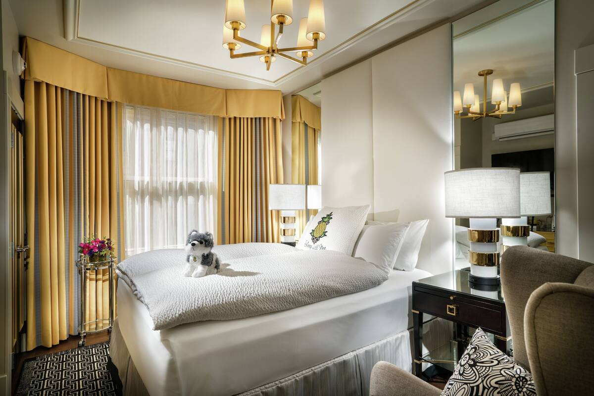 A hotel room with a large bed, a nightstand, a lamp, and a chair.