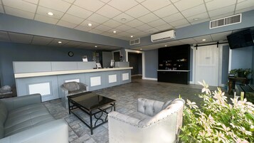Uma área de recepção com balcão, assentos e televisão.