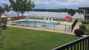 Un área de piscina con varias piscinas, un muelle cercado y vistas a un lago con barcos.