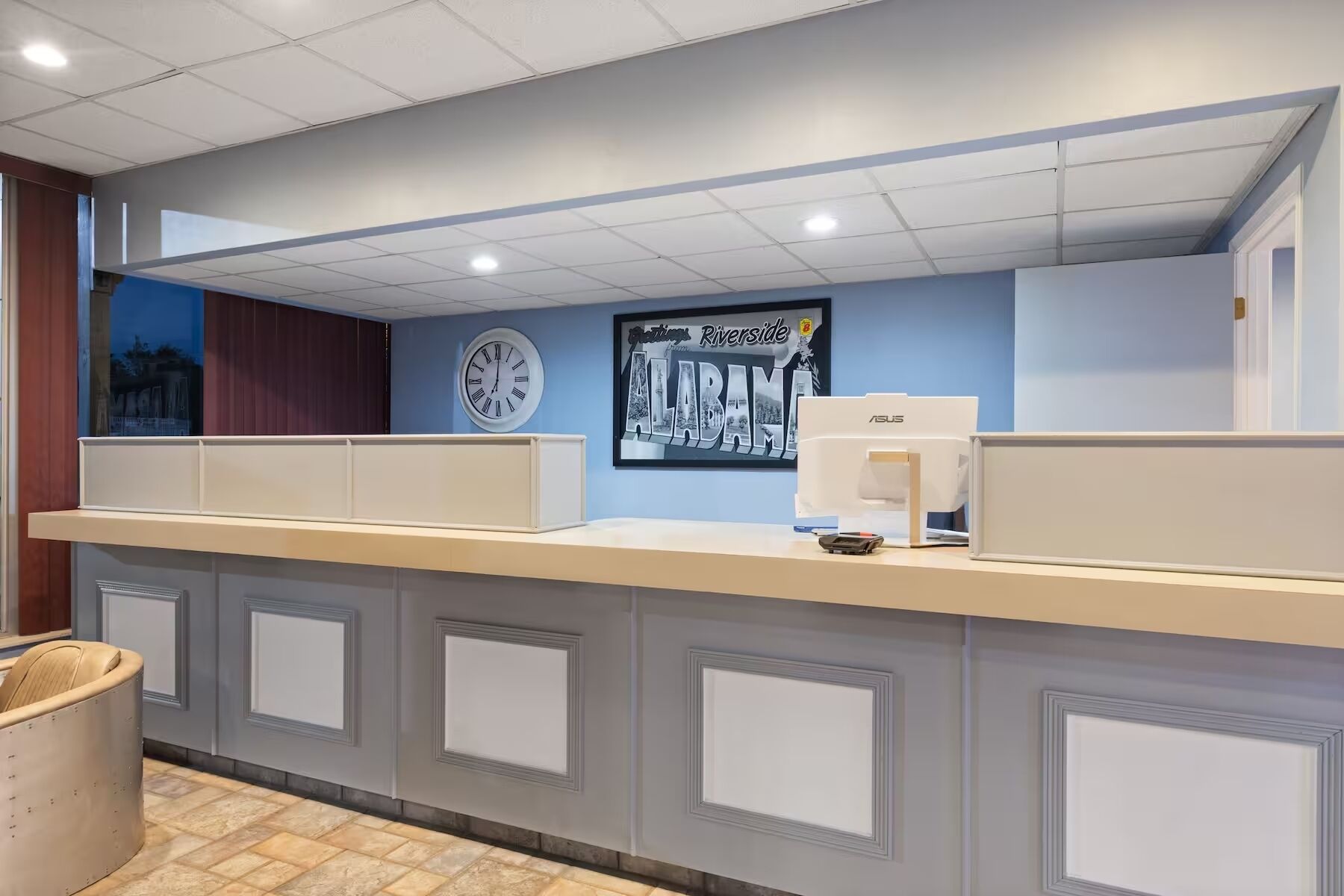 A reception desk with a clock, framed artwork, and an ASUS computer.