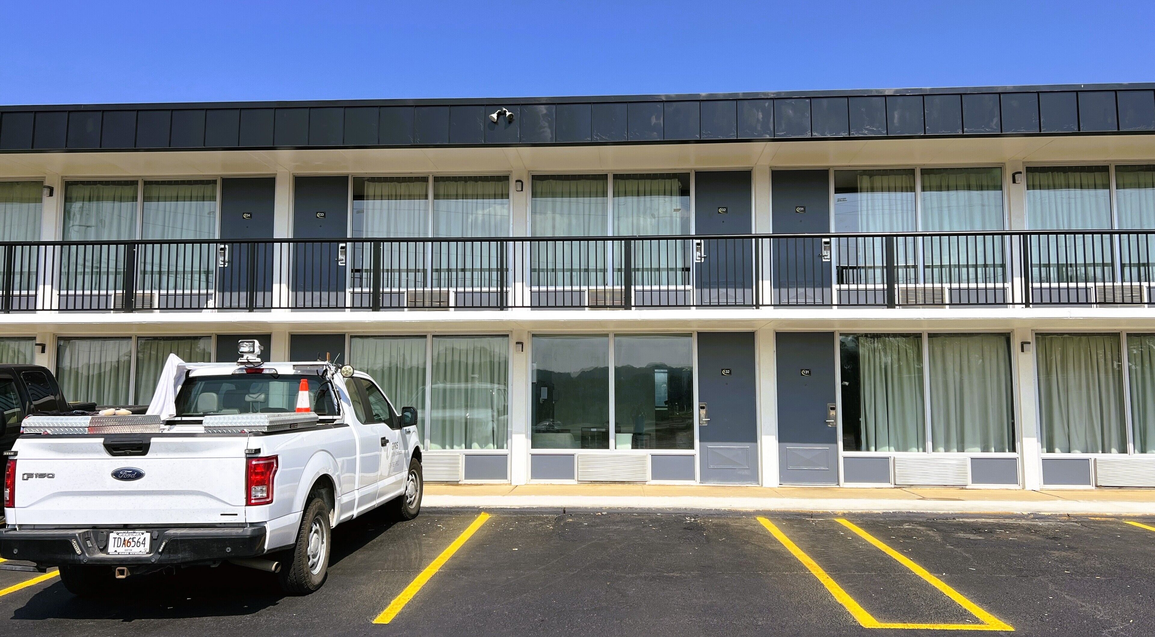 A multi-story hotel with a flat roof, large windows, and a parking lot with marked spaces.
