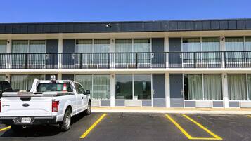 A multi-story hotel with a flat roof, large windows, and a parking lot with marked spaces.